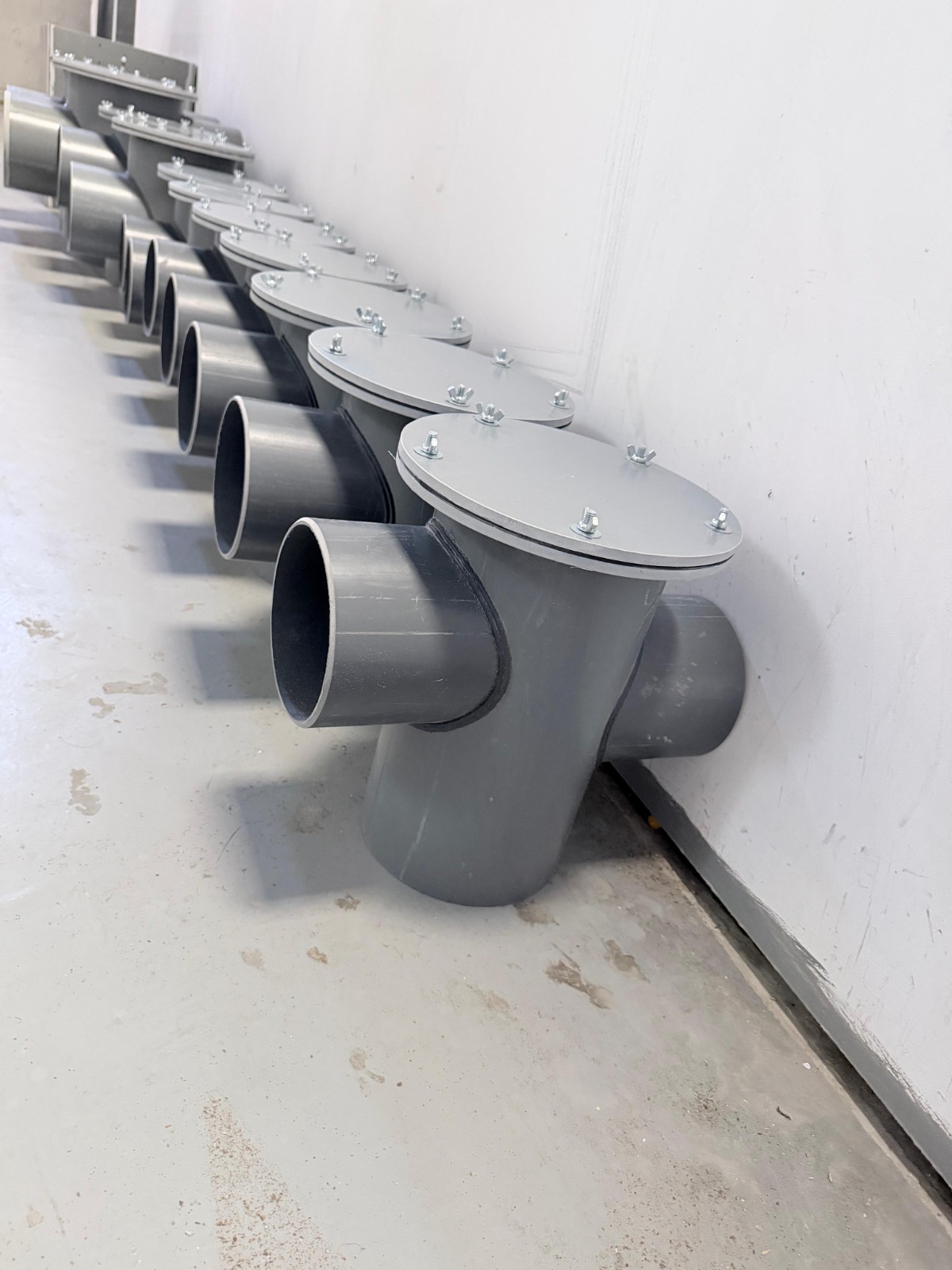 Close-up of fabricated grease traps showing bolted covers and pipe connections